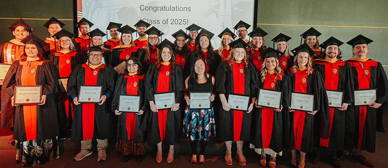 Photo of the Class of 2025 standing together in their graduation gowns holding their MS in Biotechnology Program diplomas
